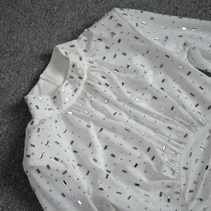 Close-up of a white mesh dress featuring elegant silver rhinestone embellishments