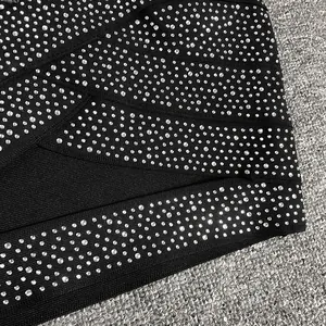 Macro detail of sparkling rhinestones on black bandage fabric for a sexy nightclub top.