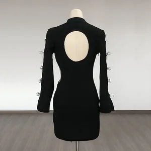 Back detail of a black long-sleeve mini dress with cut-out and crystal bow accents