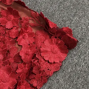 Close-up of elegant red 3D floral lace embroidery on a sophisticated evening dress fabric