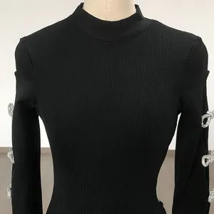 Close-up detail of a black long-sleeved rib knit dress featuring sparkling rhinestone bows.