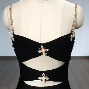 Detail of black bandage top featuring gold chain straps and ornate pearl cross charms