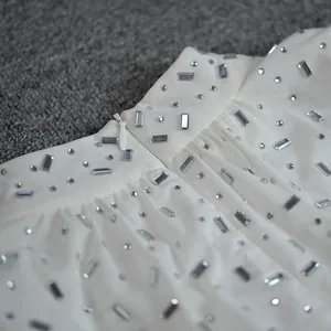 Close-up of white mesh dress waistline with sparkly rhinestones and hidden zipper