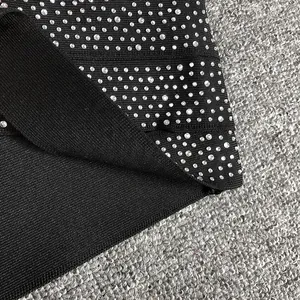 Macro view showing the detailed texture of black bandage fabric with silver rhinestones.