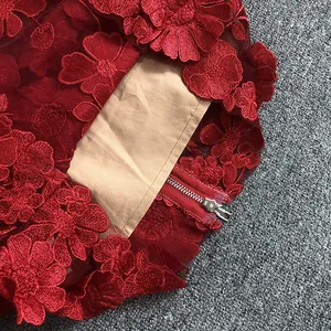 Macro view of elegant red lace dress detailing 3D floral embroidery and silver zipper