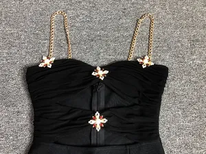 Detail view of a black sexy bandage dress with gold chain straps and ornate jeweled cross accents.