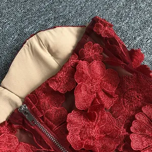 Close-up of elegant red evening dress with 3D floral embroidery and metal zipper detail.