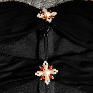 Close-up detail of black bandage dress showing hidden zipper and ornate pearl cross charms