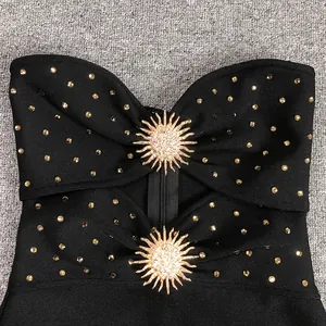 Detailed macro shot of black bandage dress featuring gold sun metal accessories and rhinestones