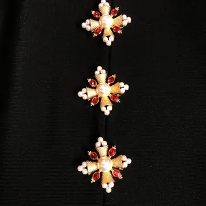 Close-up of pearl and red rhinestone cross-shaped buttons on a black bandage dress