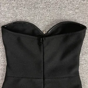 Detail of the back zipper and textured fabric of a black strapless bandage dress.