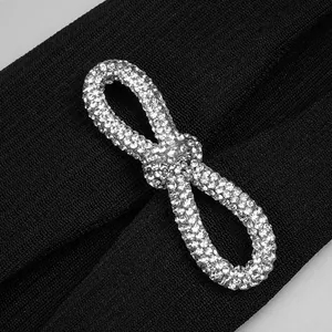 Macro detail showing a sparkling silver rhinestone bow on black ribbed bandage fabric