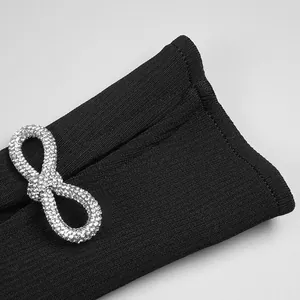 Close-up detail of black bandage dress sleeve featuring a sparkling rhinestone bow