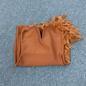 Detail eines orangefarbenen trägerlosen Kleides mit tiefem V-Ausschnitt und Federn.