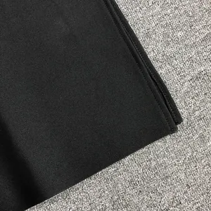 Close-up detail of high-quality black elastic bandage dress fabric with zipper.