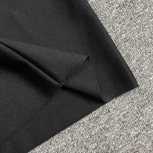 Close-up of black ribbed bandage fabric showing high-elasticity texture and hem detail.