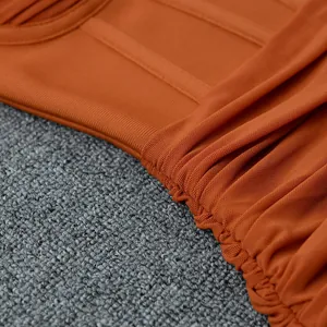 Dettaglio macro di un abito arancione che mostra l'elegante trama del tessuto a rete.