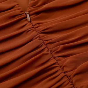 Dettaglio ravvicinato di un abito in mesh arancione drappeggiato con cerniera invisibile