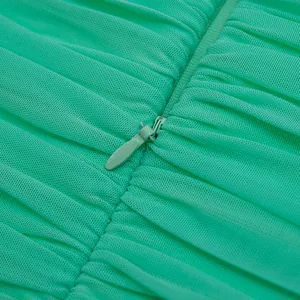 Dettaglio macro di una cerniera a scomparsa su un abito da festa in rete a pieghe verde menta