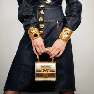 Detailweergave van donkerblauwe denim A-lijn rok met decoratieve gouden knopen.