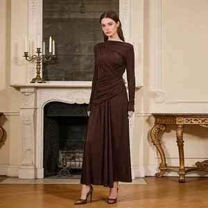 Model wearing an elegant pleated long sleeve brown maxi dress in a classical room setting
