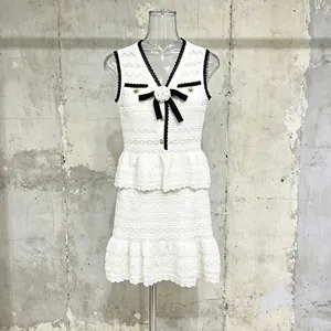Elegante set due pezzi in pizzo bianco con finiture nere e camelia su manichino trasparente.