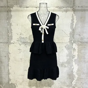 Elegante completo due pezzi in maglia nera con profili bianchi e fiore di camelia.