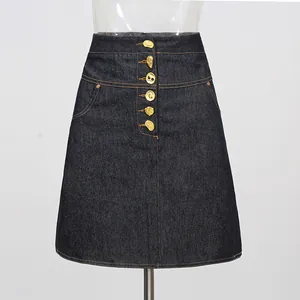 Detailopname van donkere denim A-lijn rok met unieke gouden artistieke knopen en stiksels