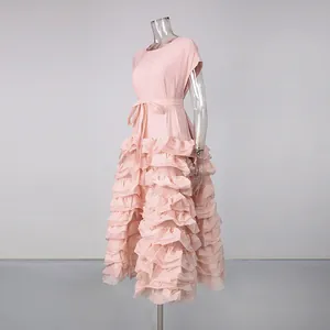 Detailansicht eines blassrosa Kleides mit gestuftem Rüschensaum und Bindegürtel.