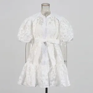 Detailed view of white puff sleeve lace dress with hollow jacquard and bow tie waist.