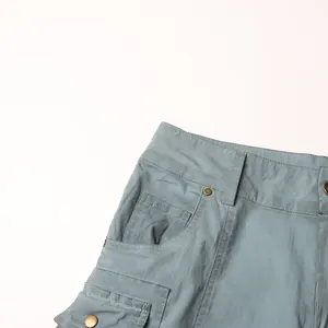Dettaglio della tasca e dei bottoni in metallo su jeans cargo a zampa a vita bassa