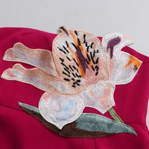 Detailed macro view of delicate floral embroidery on a vibrant magenta cocktail dress