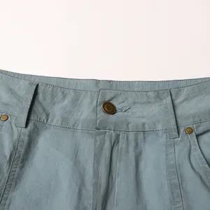 Dettaglio di pantaloni cargo a vita bassa con bottoni in ottone e cuciture rifinite