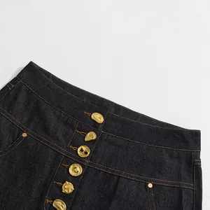 Detailopname van een denim A-lijn rok met unieke gouden knopen in een enkele rij.
