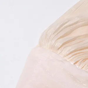 Détail en gros plan du tissu plissé scintillant et de la texture d'une robe beige chic