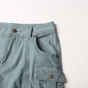 Primo piano dettagliato di pantaloni cargo a vita bassa con bottoni metallici e tasca a patta