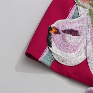 Exquisite macro detail of heavy floral embroidery on high-quality fuchsia satin fabric