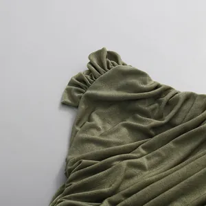 Macro close-up showing the ruffled texture and draped fabric of an olive green dress