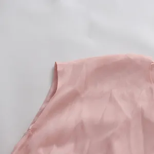 Detaillierte Nahaufnahme der Schulternaht eines rosa Kleides mit zarter Stofftextur