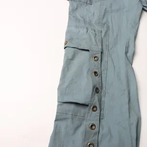 Dettaglio di pantaloni cargo azzurri con occhielli metallici vintage e design tasca.
