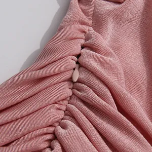 Detail shot of concealed zipper on elegant pink ruched maxi dress fabric texture.