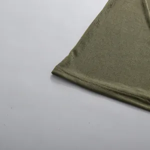 Close-up of the pleated fabric and hemline of this green off-shoulder maxi dress.