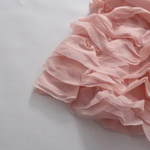 Nahaufnahme der zarten rosa Volantschichten eines leichten Chiffonkleides Details