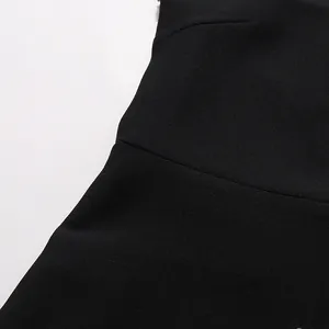 Close-up detail showing the fine black fabric texture and neat horizontal seam of a dress