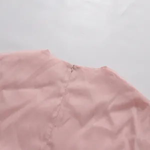 Detailansicht des versteckten Rückenreißverschlusses an einem rosa Kleid aus weichem Stoff.