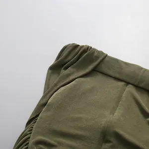 Close-up detail of the elegant pleated off-the-shoulder neckline on a green textured dress