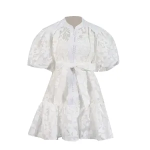 Detailed view of elegant white hollow-out floral lace dress with puff sleeves and tie