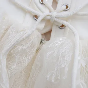 Detailansicht der Schnürung und des Mesh-Spitzenstoffs an einem cremefarbenen Kleid