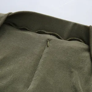 Close-up detail of the invisible zipper and pleated fabric texture on olive green dress