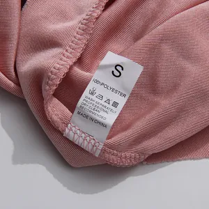 Detailed macro view of the white wash care label on a pink pleated polyester fabric garment